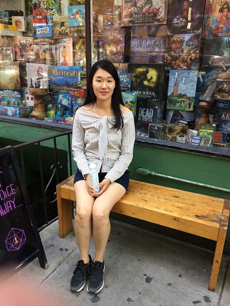 Jiyeon Kim, a fourth-year graduate student in the department of economics, sits on a bench in front of a store 