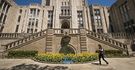 Student walking in front of the base of the Cathedral of Learning